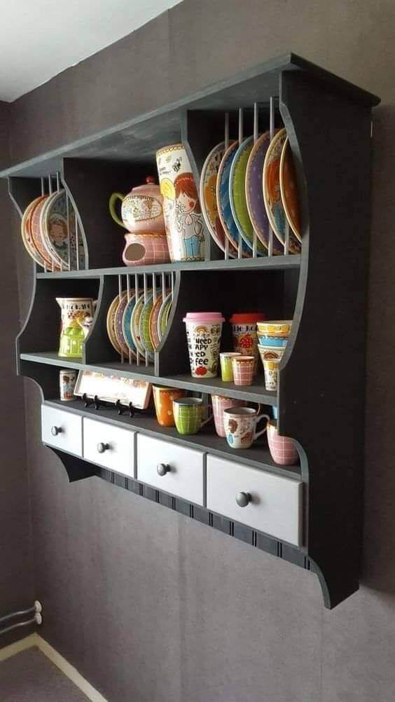 Portavajillas de pared en color gris con estantes para platos y tazas de colores, con cajones en la parte inferior, ideal para cocinas modernas y organizadas.