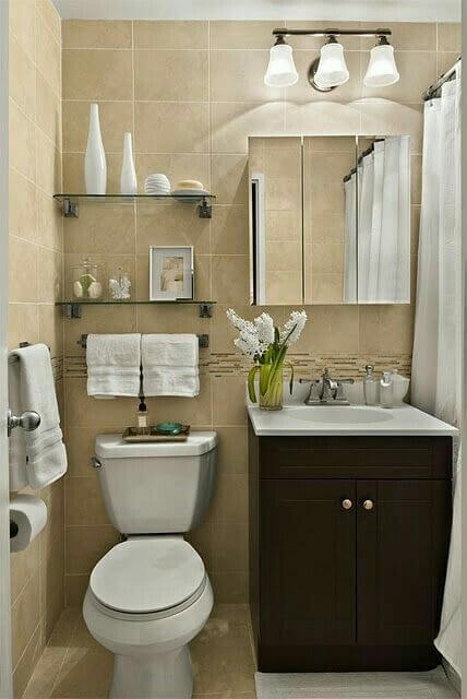 Repisa de cristal en baño pequeño con toallas y decoraciones sencillas, creando un ambiente organizado y elegante. Ideal para espacios reducidos.