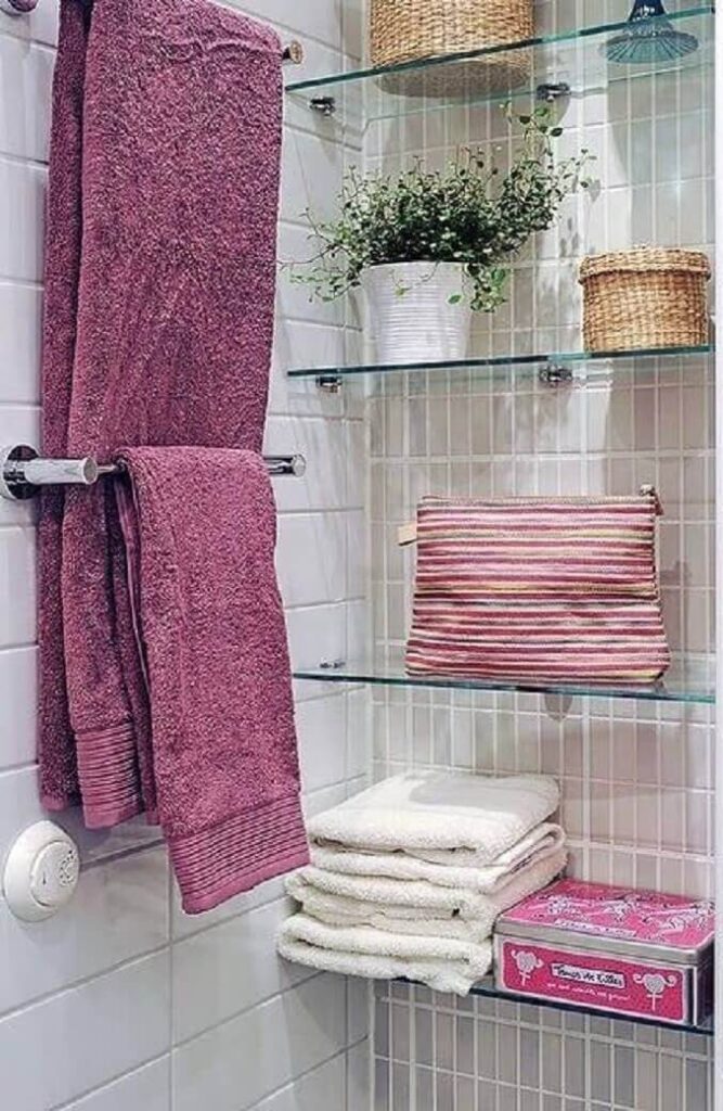 Repisa de cristal con toallas organizadas y detalles decorativos en baño. Diseño moderno y funcional que optimiza el espacio sin perder elegancia.